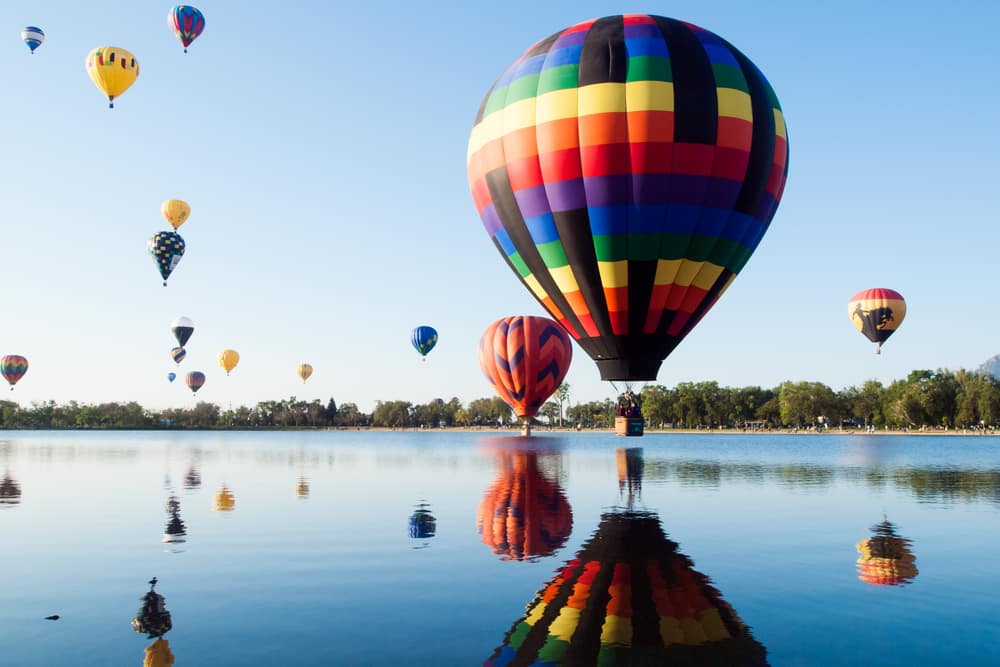 Hot air balloon festival above a lake.
